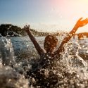 A child swimming in a river has fun splashing water.