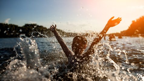 A child swimming in a river has fun splashing water.