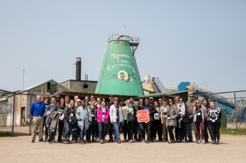 A group of people pose in front of a silo.