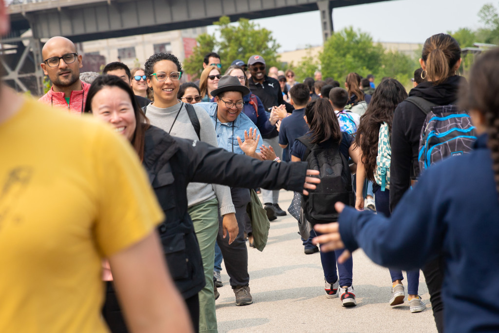 A group of kids in a line, high-five a group of adults in a parallel line.