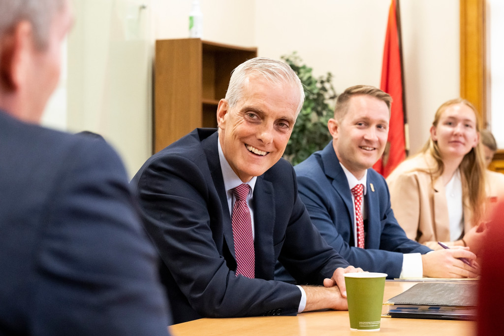 At center, U.S. Secretary of Veterans Affairs Denis McDonough listens to Jim Gingras, graduate student in International Relations and retired lieutenant colonel with the U.S. Air Force while sitting at a conference table.