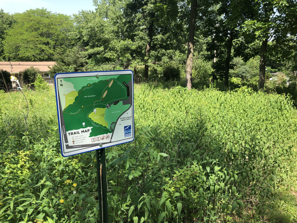 A sign is shown in a wooded park.