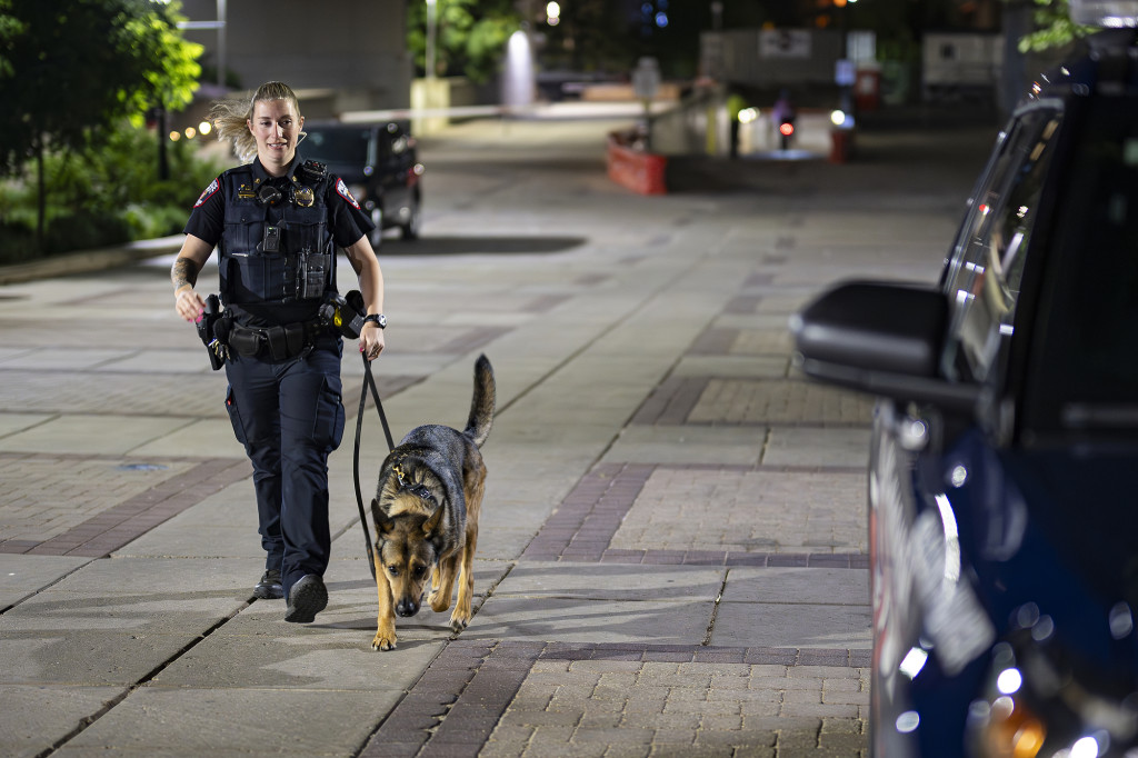 A police officer in uniform walks a dog.