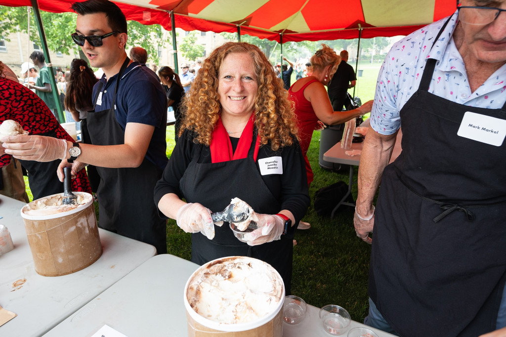 Chancellor Jennifer Mnookin smiles wide as she works the serving line. She is scooping ice cream into a cup as others around her do the same.
