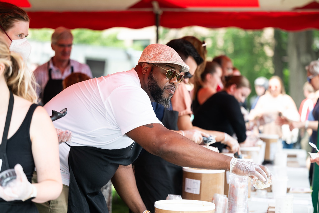 LaVar Charleston works the ice cream serving line under a red and white tent during a staff appreciation ice cream social on Bascom Hill.