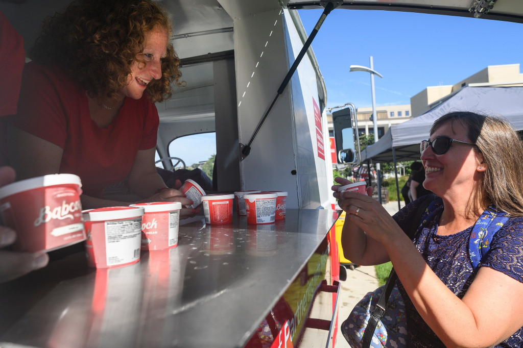 Chancellor Jennifer Mnookin stands in the window of the ice cream truck and hands out ice cream cups.