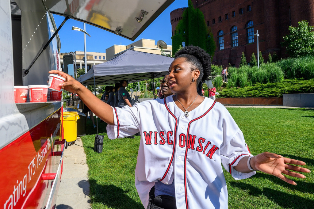 A woman wearing a UW–Madison baseball jersey accepts an ice cream cup from the window of the ice cream truck.