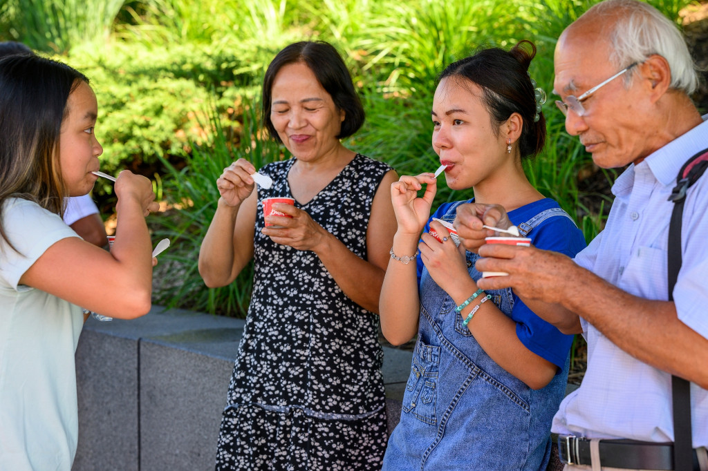 Four people smile as they stand together eating ice cream.