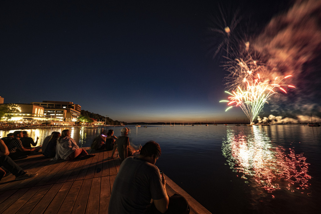People sit on a dock by the Terrace to watch a fireworks display.