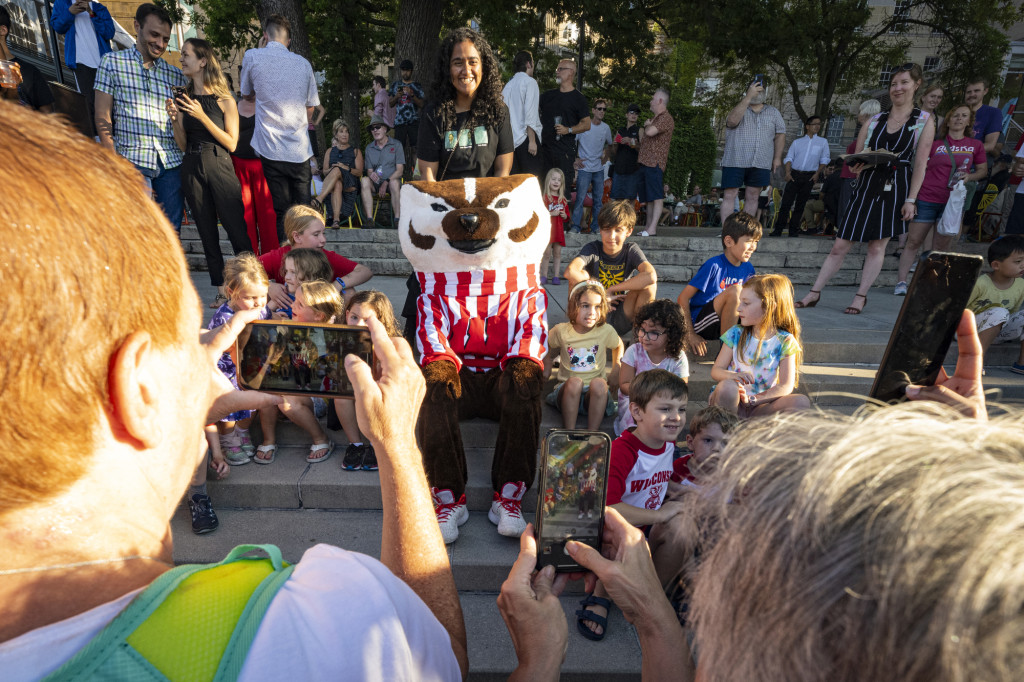 Bucky Badger sits on the Terrace steps with a crowd of children.