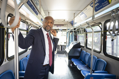 Charles Isbell stands and holds on to a wrist strap on a public bus.