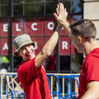 To men wearing red shirts give each other a high-five.