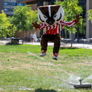 Bucky Badger jumps up = to avoid being hit with a lawn sprinkler.