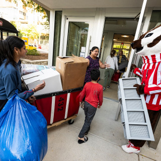 Bucky Badger helps students carry their belongings into a residence hall.