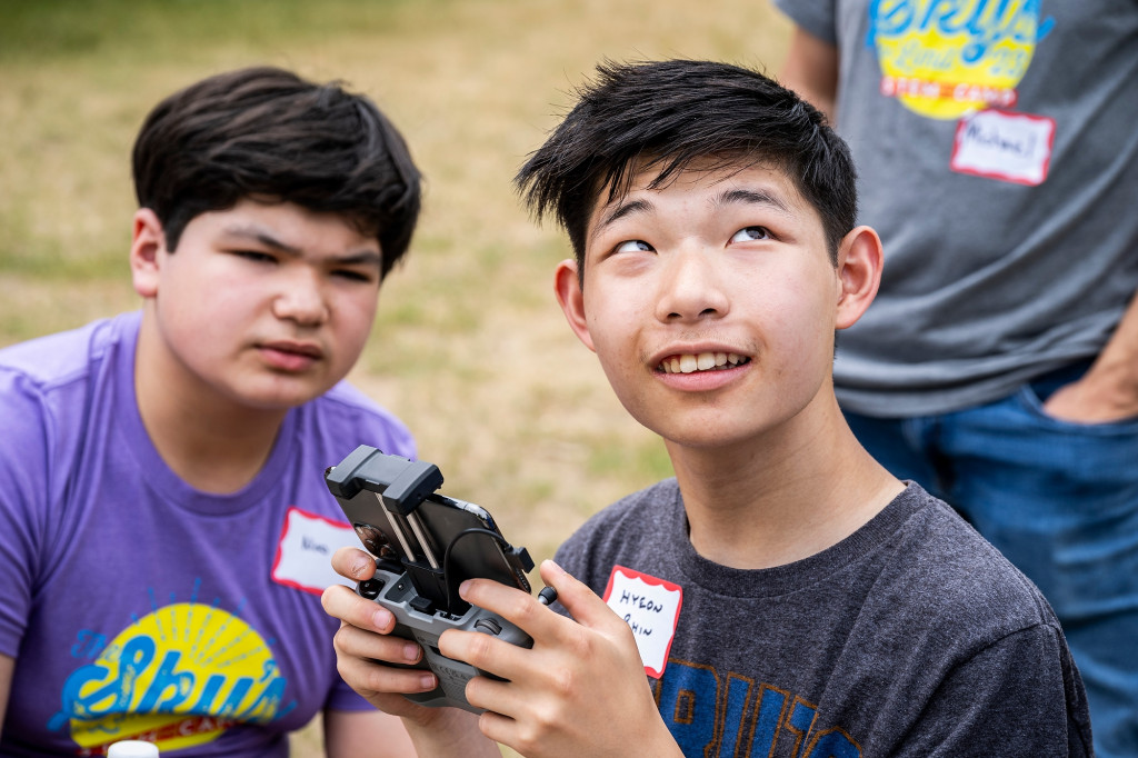 Two people work a remote for a drone.