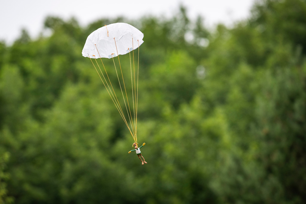A toy moose floats to the ground on a parachute.