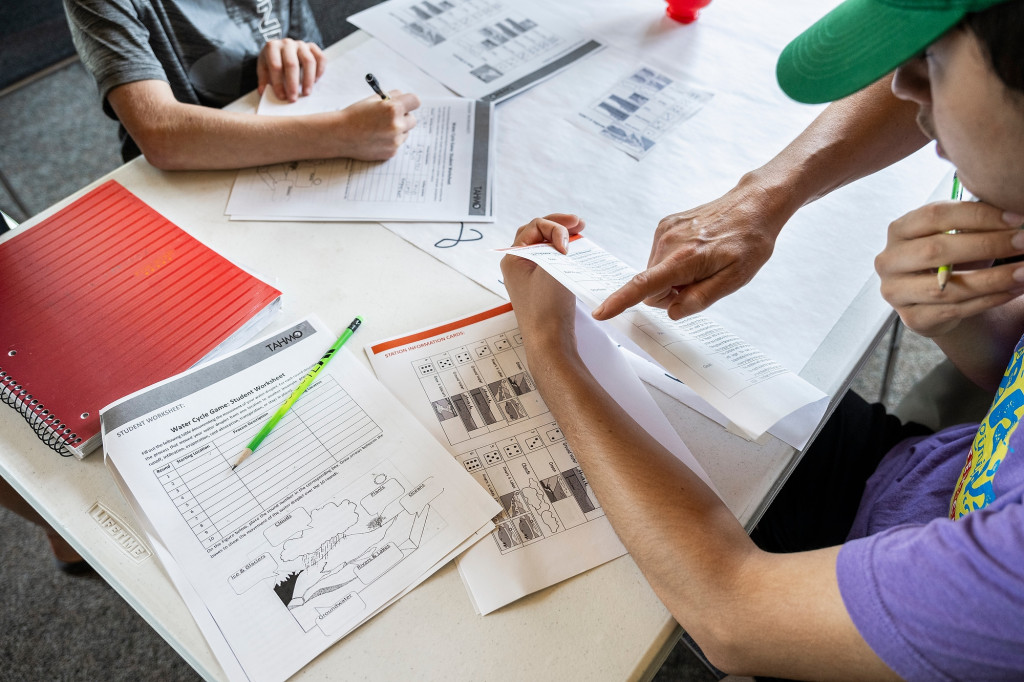 A youth looks through a pile of worksheets.