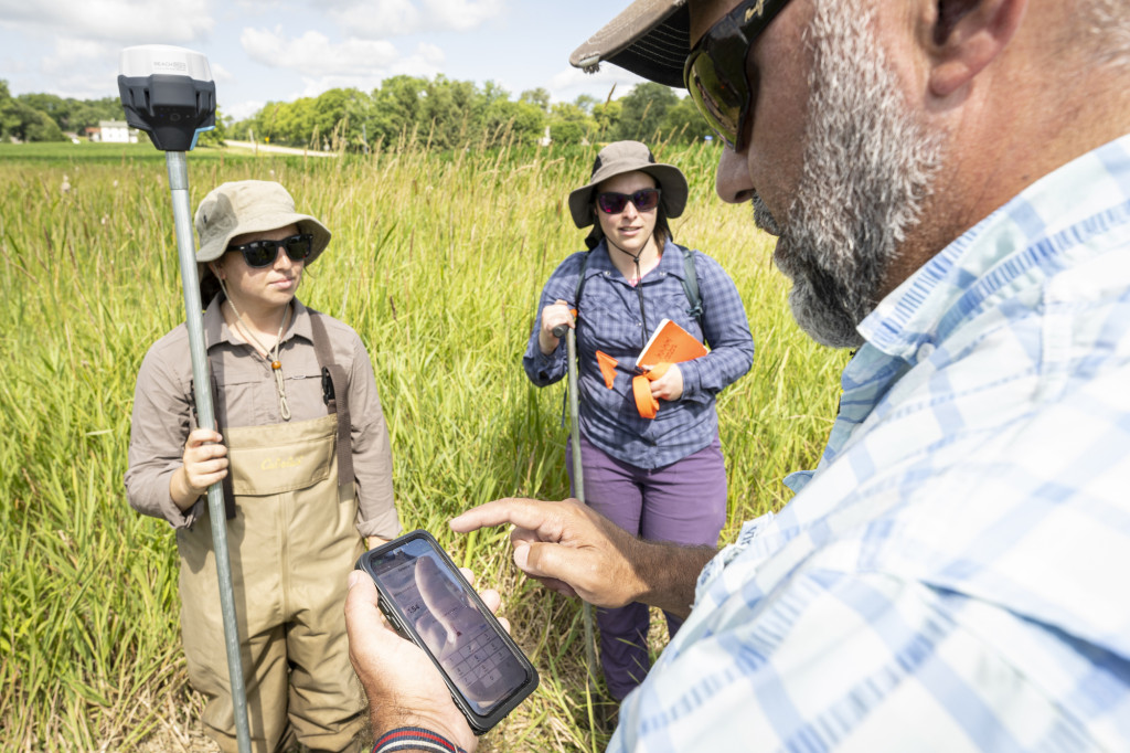 Two students talk with a teacher.