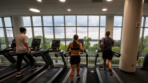 People run on treadmills while looking out the window.