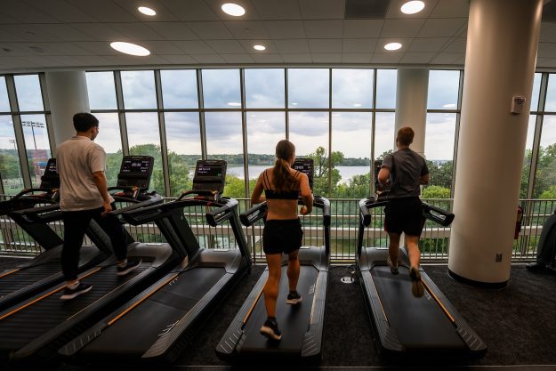 People run on treadmills while looking out the window.