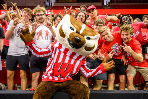 Bucky Badger poses with a large group of students who lean in to fill the frame.