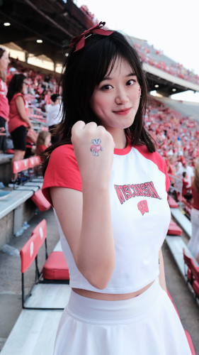 W woman in a Wisconsin shirt stands in the stadium.