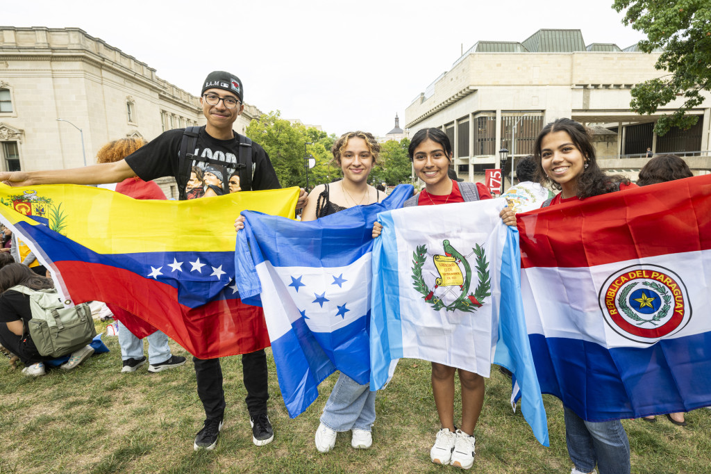 Four people stand in a row holding up flags.