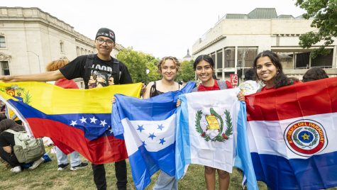 Four people stand in a row holding up flags.