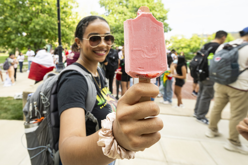 A woman holds out a popsicle-like treat.