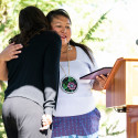 A woman hugs another woman.