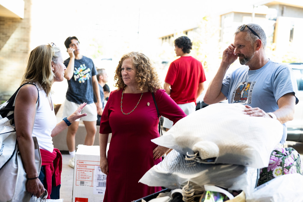 Surrounded by move-in supplies and belongings, Chancellor Mnooking speaks with parents of UW students.