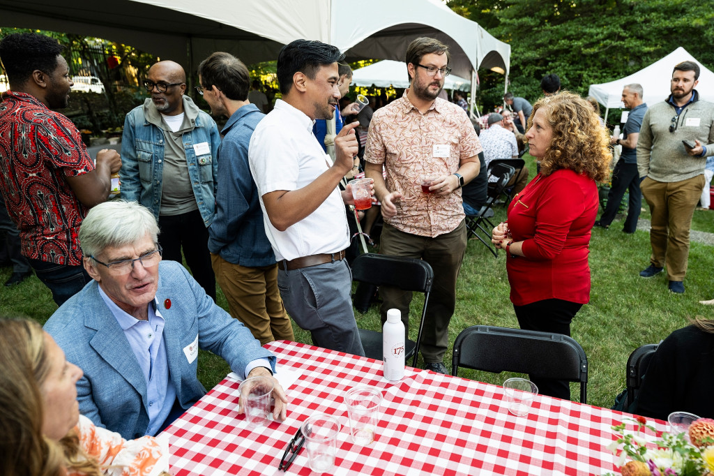 Amid a crowd of picnickers, Chancellor mnookin listens in conversation with a new faculty member and his partner.