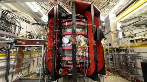 A large, red and silver chamber sits in the middle of a physics engineering lab.