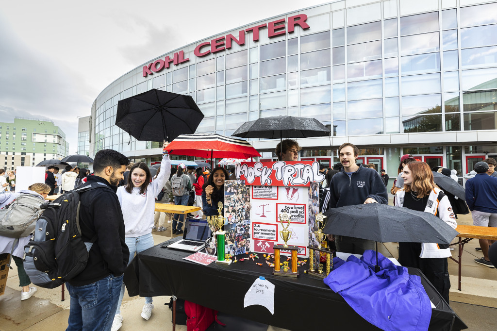 Two people talk at a booth outside of the Kohl Center.