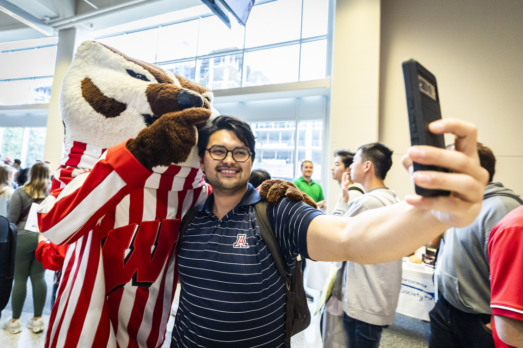 A student hugs Bucky Badger and takes a photo.