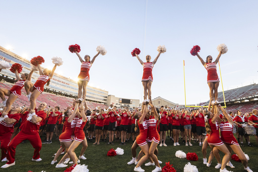 Members of the spirit squad hoist some of their group into the air waving red and white pompoms.