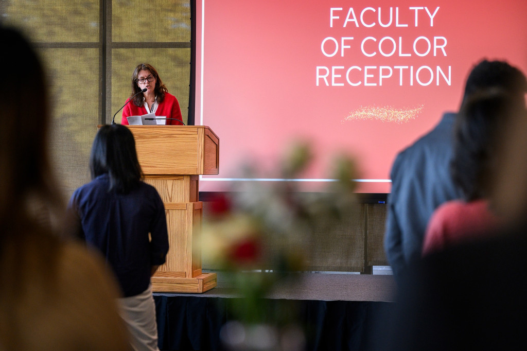 Susan Thibeault speaks from a podium. The screen behind her reads Faculty of Color Reception.