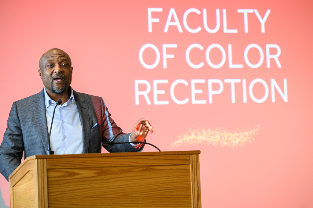 Charles Isbell speaks from a podium. The screen behind him reads Faculty of Color Reception.