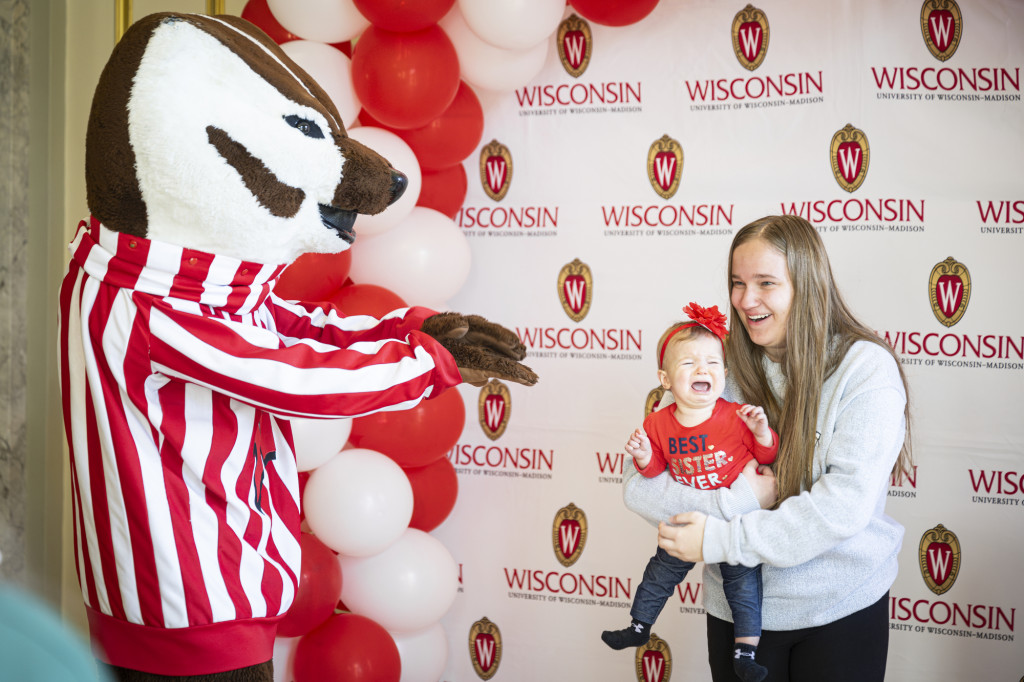 Undergraduate Kylie Cofoid (right) and her sister Myla get ready to take a photo with UW mascot Bucky Badger.