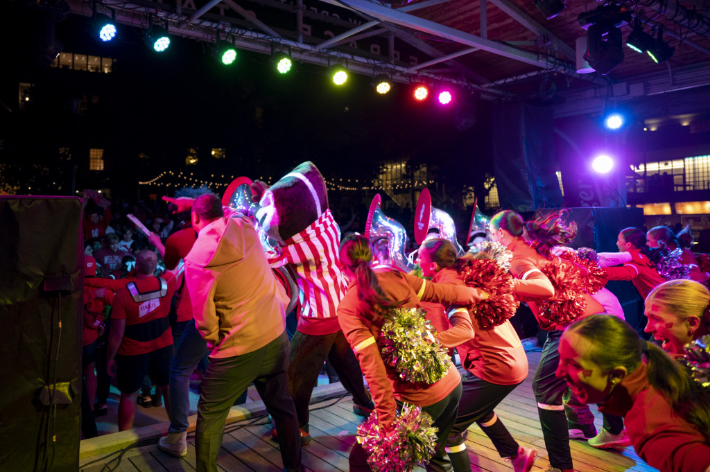 In a photo taken at night from back stage, Bucky Badger and members of UW's Spirit Squad and Marching Band lean out to the crowd during their performance.