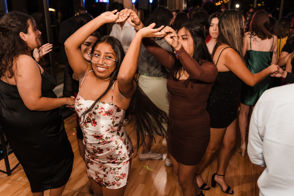 A student in a floral dress twirls with another student on the dance floor.