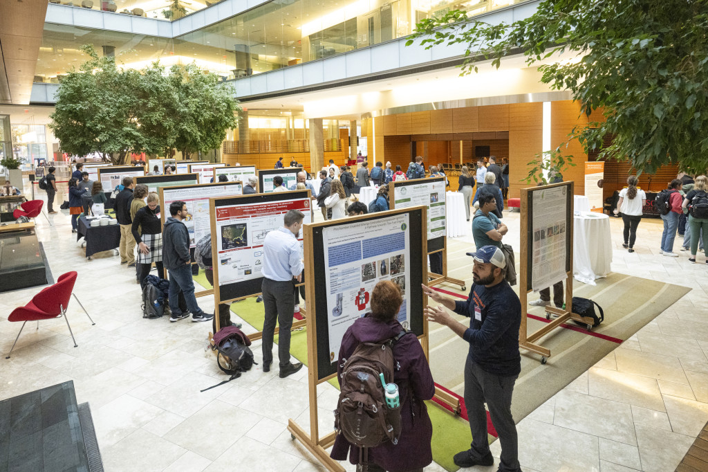 A view from above of rows of posters being presented, with people walking around and looking at them.