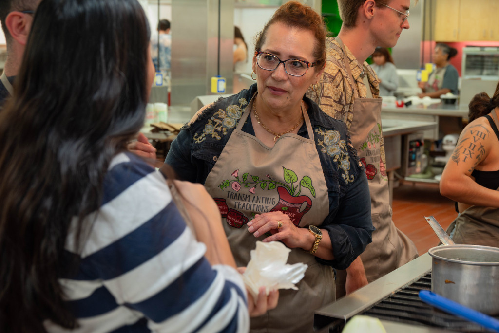 A woman wearing an apron talks to students about masa, a four or corn dough.