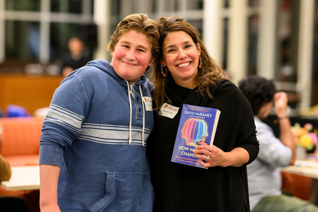 Two people stand holding a book and smiling for the camera.