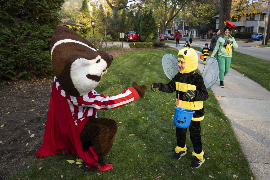 Bucky Badger, dressed as Dracula, shakes hands with a bumblebee, or perhaps a trick or treater dressed as a bumblebee.