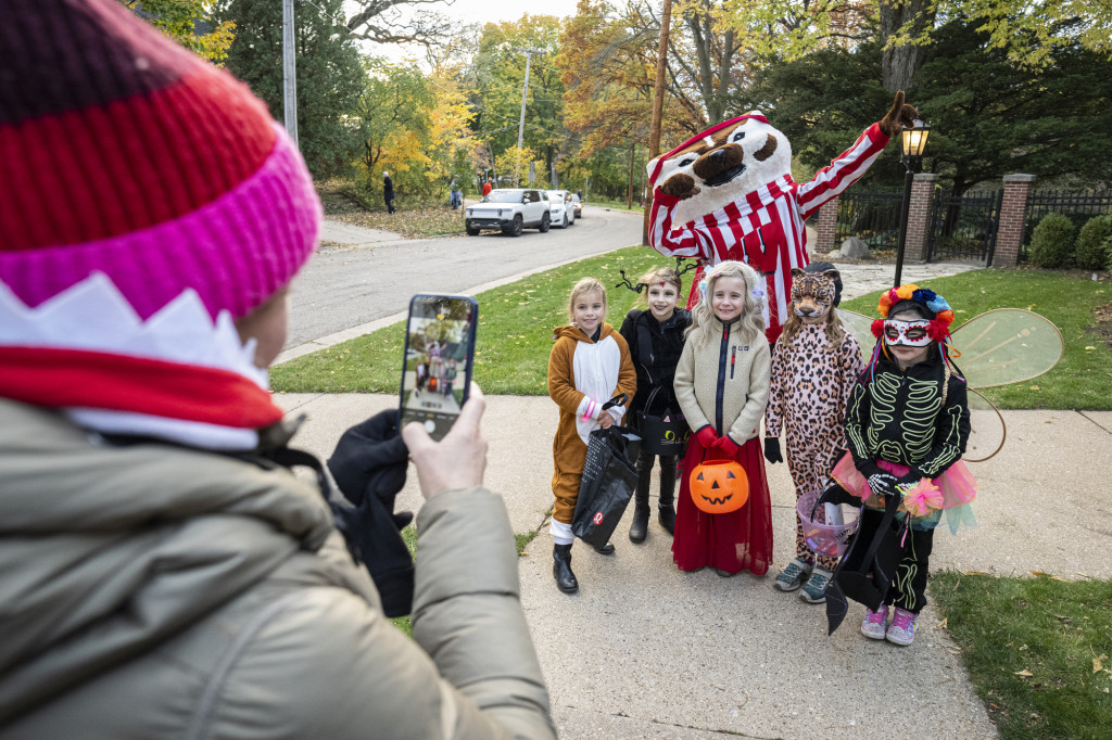 Bucky Badger takes a photo with a group of trick or treaters on Halloween at Olin House.