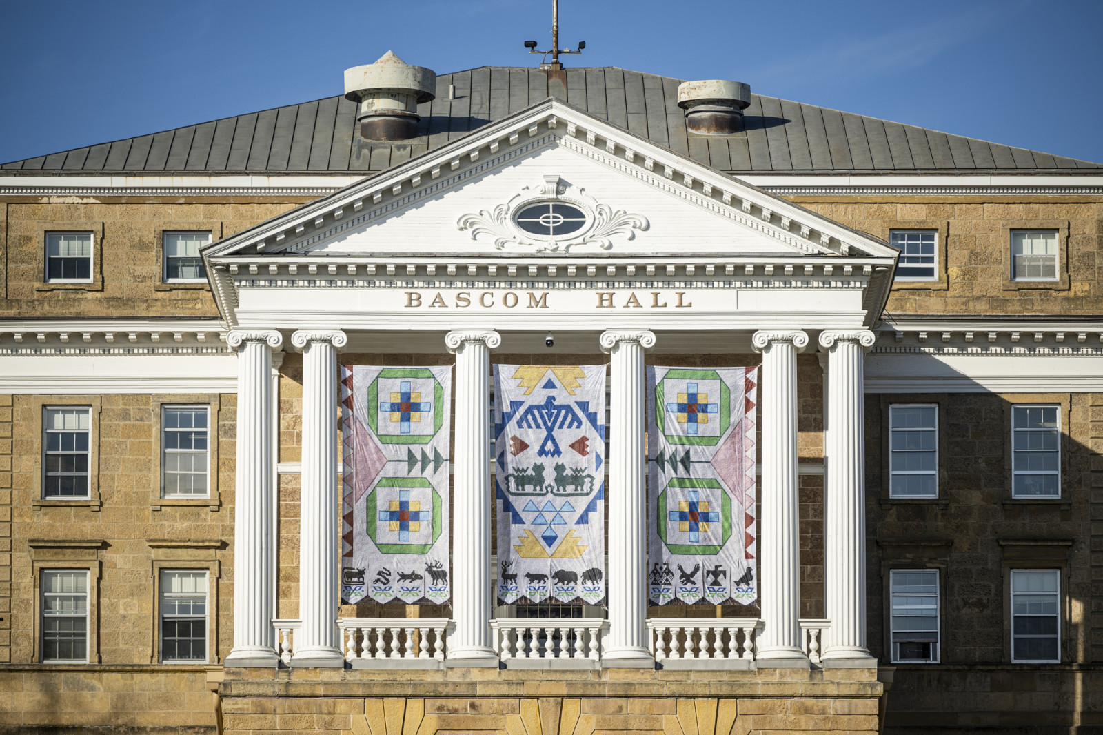 A closeup view of the center columns of Bascom Hall where the Seed by Seed banners hang on a sunny day.