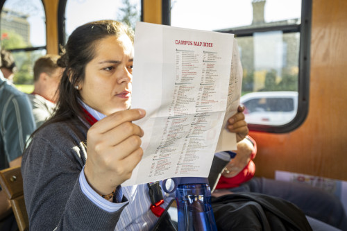 A woman on the bus reads a pamphlet containing a campus map.