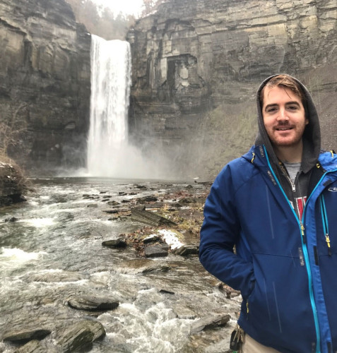 A photo of Nick Sullivan standing in front of a waterfall.