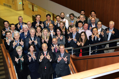 A group of people smile for the camera and form a W sign with their hands.